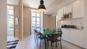 Et moderne køkken med spiseplads, med et grønt bord, sorte stole og en hængende lampe.