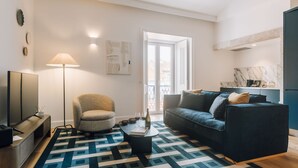 A modern living room with a sofa, armchair, coffee table, and a TV. - Abrantes 50 House - One Bedroom Deluxe APT (Lisbon)