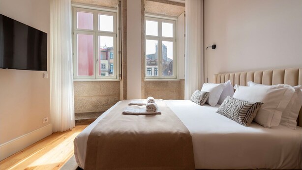 Habitación de hotel con una cama grande, dos ventanas, un televisor de pantalla plana y vistas a la ciudad.
