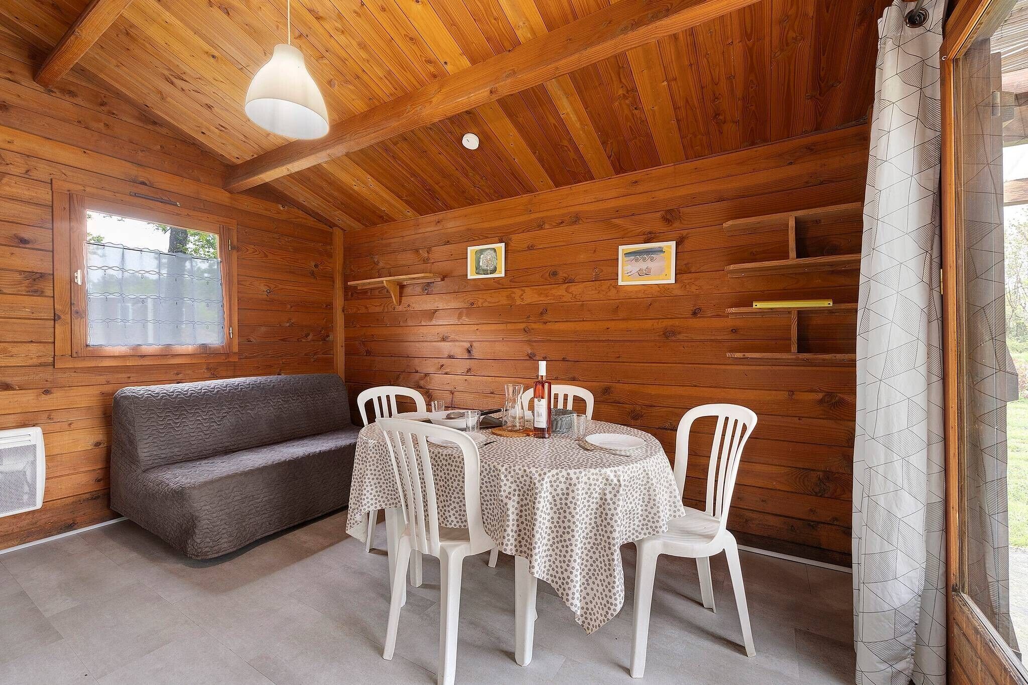 Ein Holzblockhaus-Interieur mit einem runden Tisch, weißen Stühlen, einer Couch und einer Deckenleuchte.