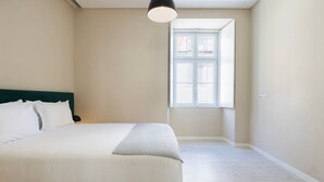 A bedroom with a bed, a window, and a light fixture. - Carmo 43 | Apartment 203 (Lisboa)