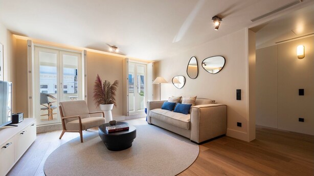 Un salon moderne avec un canapé, des fauteuils, une table basse et un téléviseur.