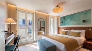 Une chambre d’hôtel moderne dotée d’un grand lit, d’un bureau, d’une chaise, d’un balcon et offrant une vue sur la ville.