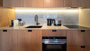 Une cuisine moderne avec des meubles en bois, un évier en acier inoxydable, une machine à café et un lave-vaisselle.