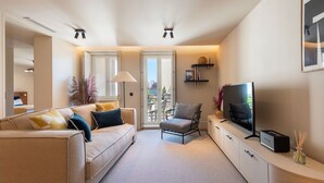 Un salon moderne avec un canapé, un fauteuil, une télévision et une vue sur le balcon.