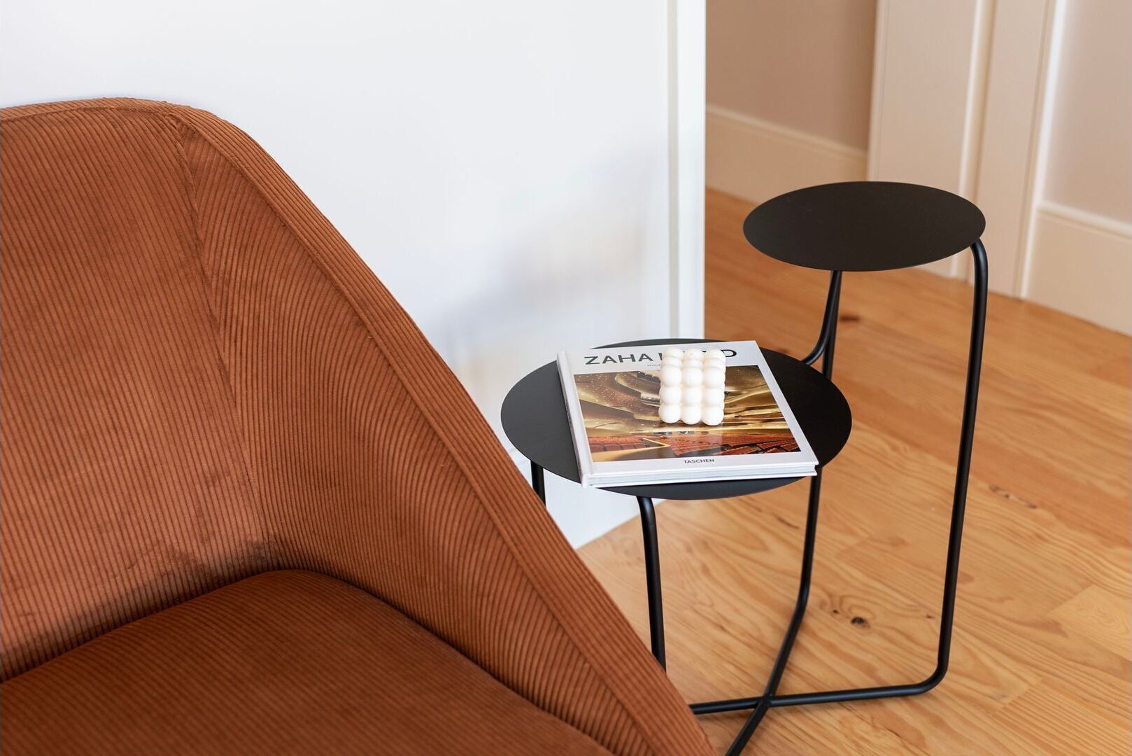 A brown chair with a magazine on a small black table beside it.
