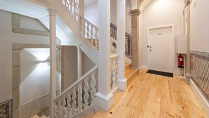 A hallway with a wooden floor, white walls, and a white door marked with the number 301. - Ando Living - Flores 200 Townhouse - 301 (Porto)