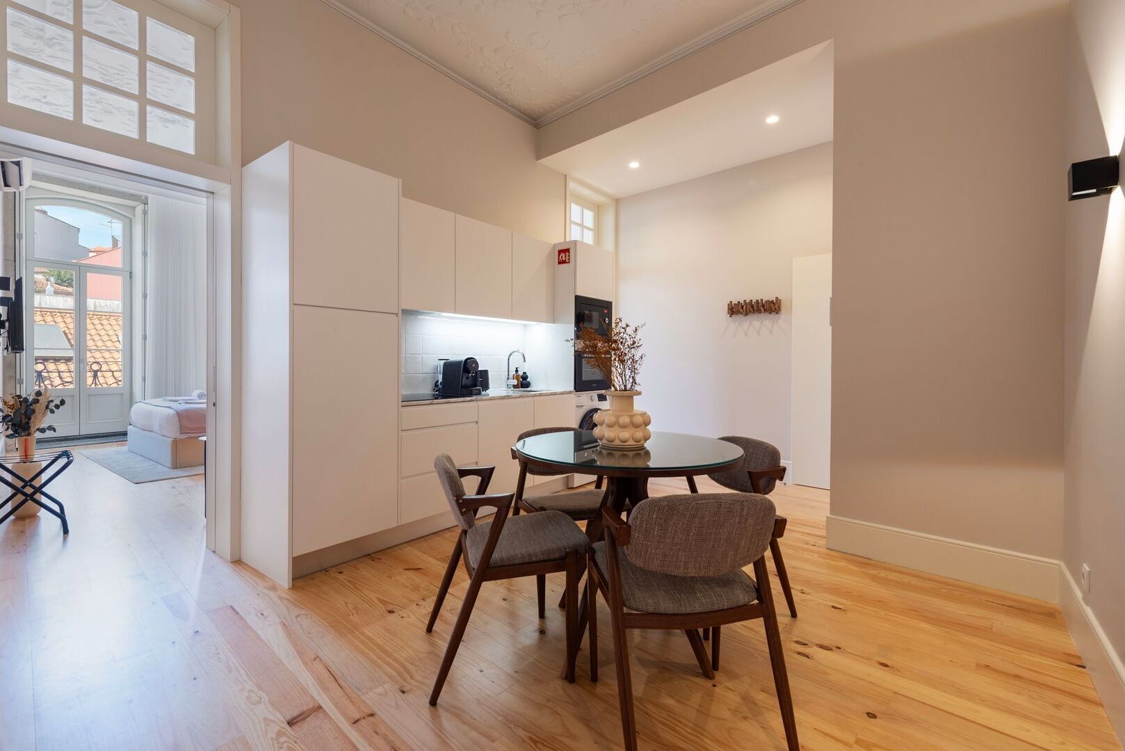 Una cocina moderna con armarios blancos, una mesa redonda para comer y suelo de madera.