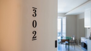 Una porta con il numero 302 che dà accesso a una cucina moderna, con un'area pranzo visibile sullo sfondo.