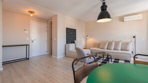 A modern living room with a sofa, a green table, and a black pendant light. - Carmo 43 | Apartment 302 (Lisboa)