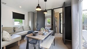 A modern interior with a dining area, a sofa, and a bench. - “Riviera 48” Mobile Home with Shared Pool, Communal Terrace, and Wi-Fi (Saint-Gervais)