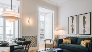 Uma sala de estar moderna com um sofá verde, uma mesa de jantar com cadeiras e uma janela grande.
