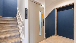A staircase leading to a landing with a door marked with a fire exit sign. - Carmo 43 | Apartment 400 (Lisboa)