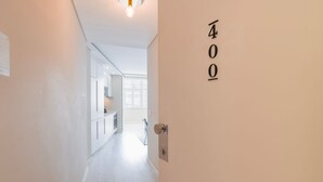 A hallway with a door labeled "400" leading to a kitchen area with white cabinets and a microwave. - Carmo 43 | Apartment 400 (Lisboa)