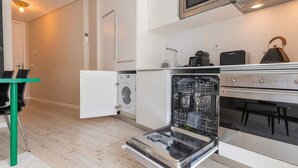 A compact kitchen with a dishwasher, a microwave, and a kettle. - Carmo 43 | Apartment 400 (Lisboa)