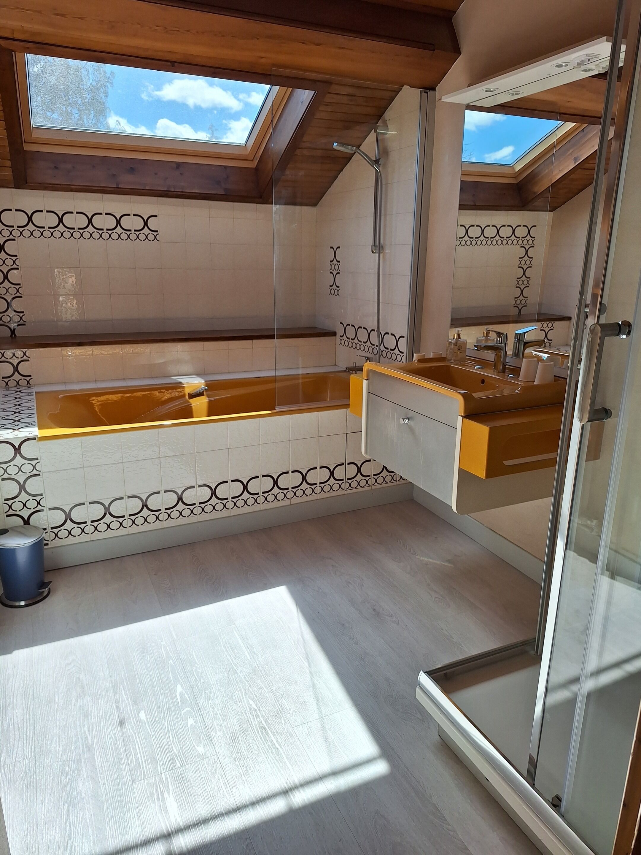 A modern bathroom with a skylight, a bathtub, and a shower area.