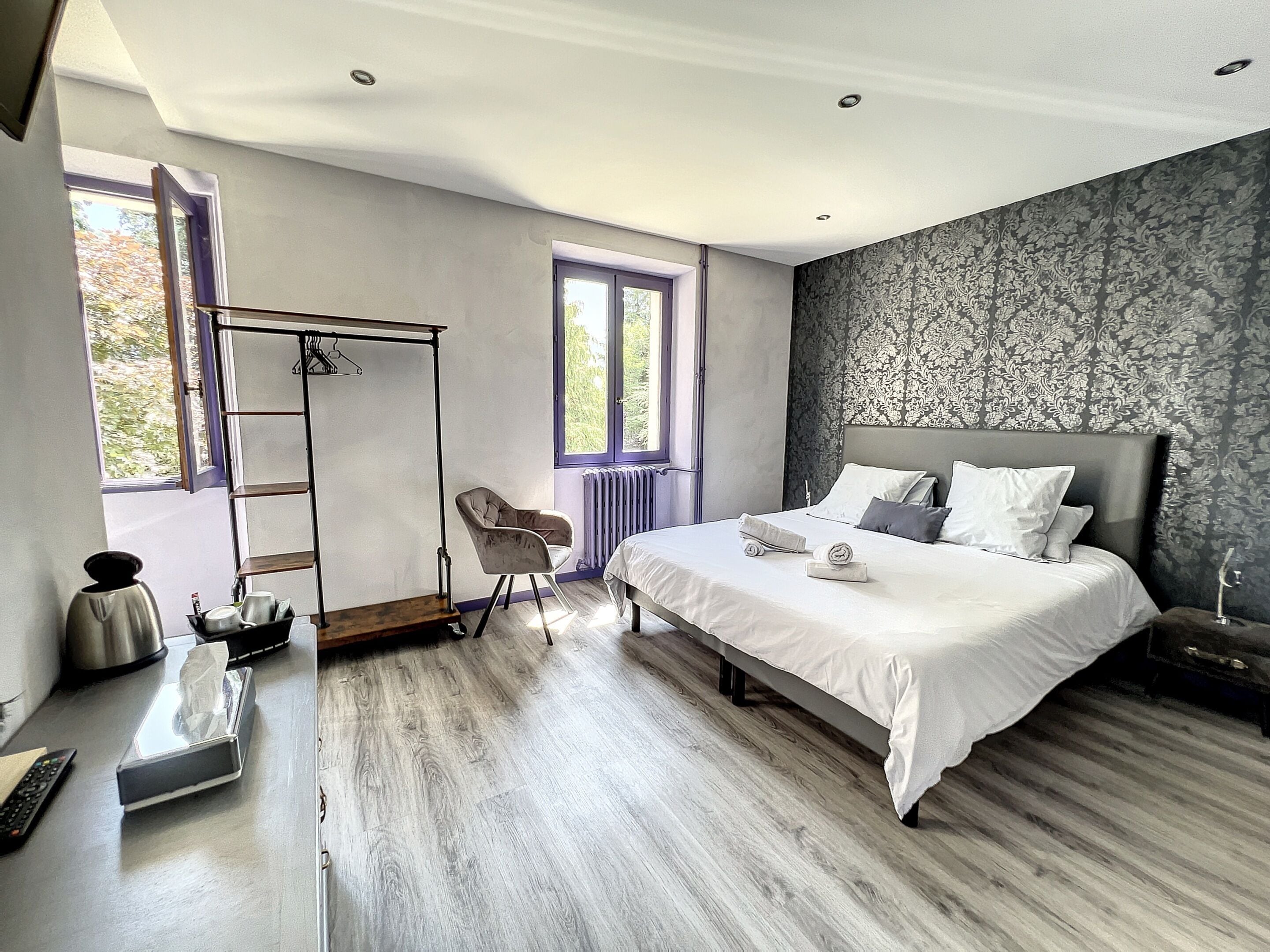 Une chambre avec un grand lit, une chaise, un radiateur et une fenêtre.
