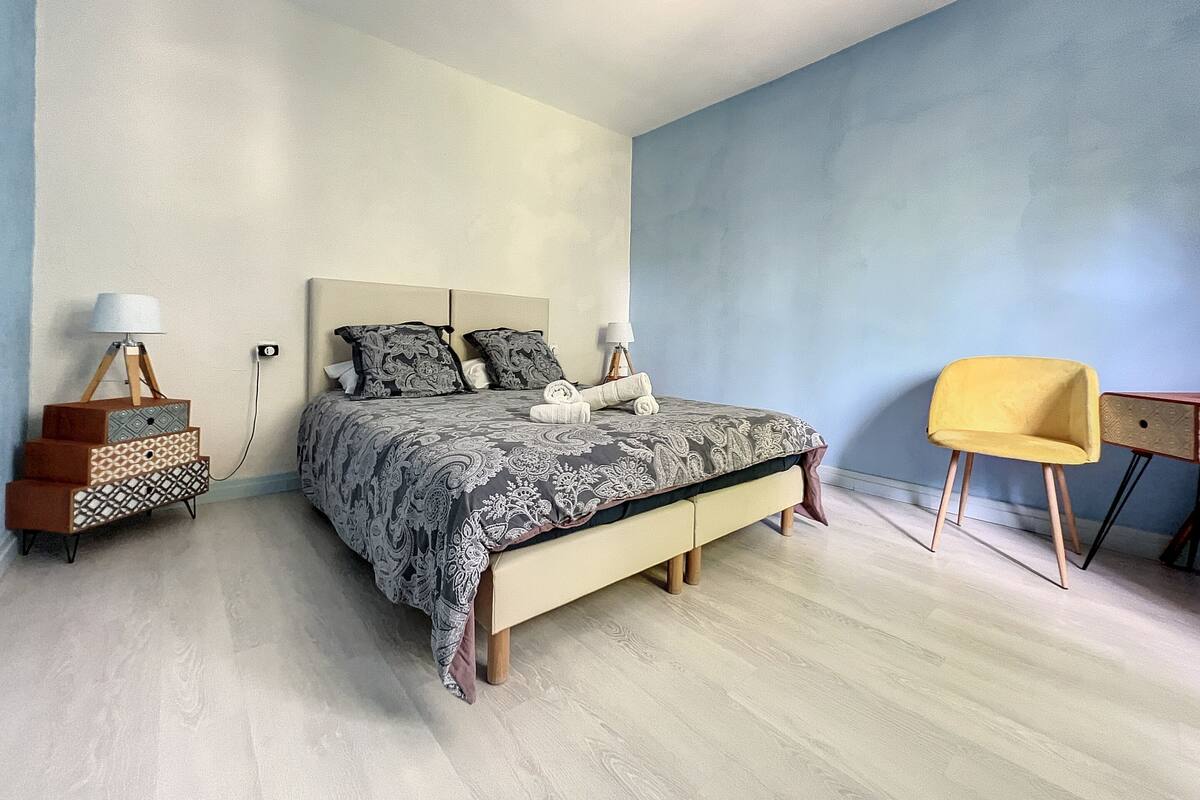 A bedroom with a bed, bedside lamps, a chair, and a small table.
