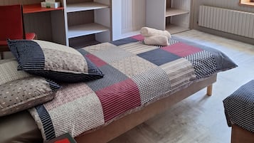 Un dormitorio con una cama, una silla roja, un armario y un espejo.