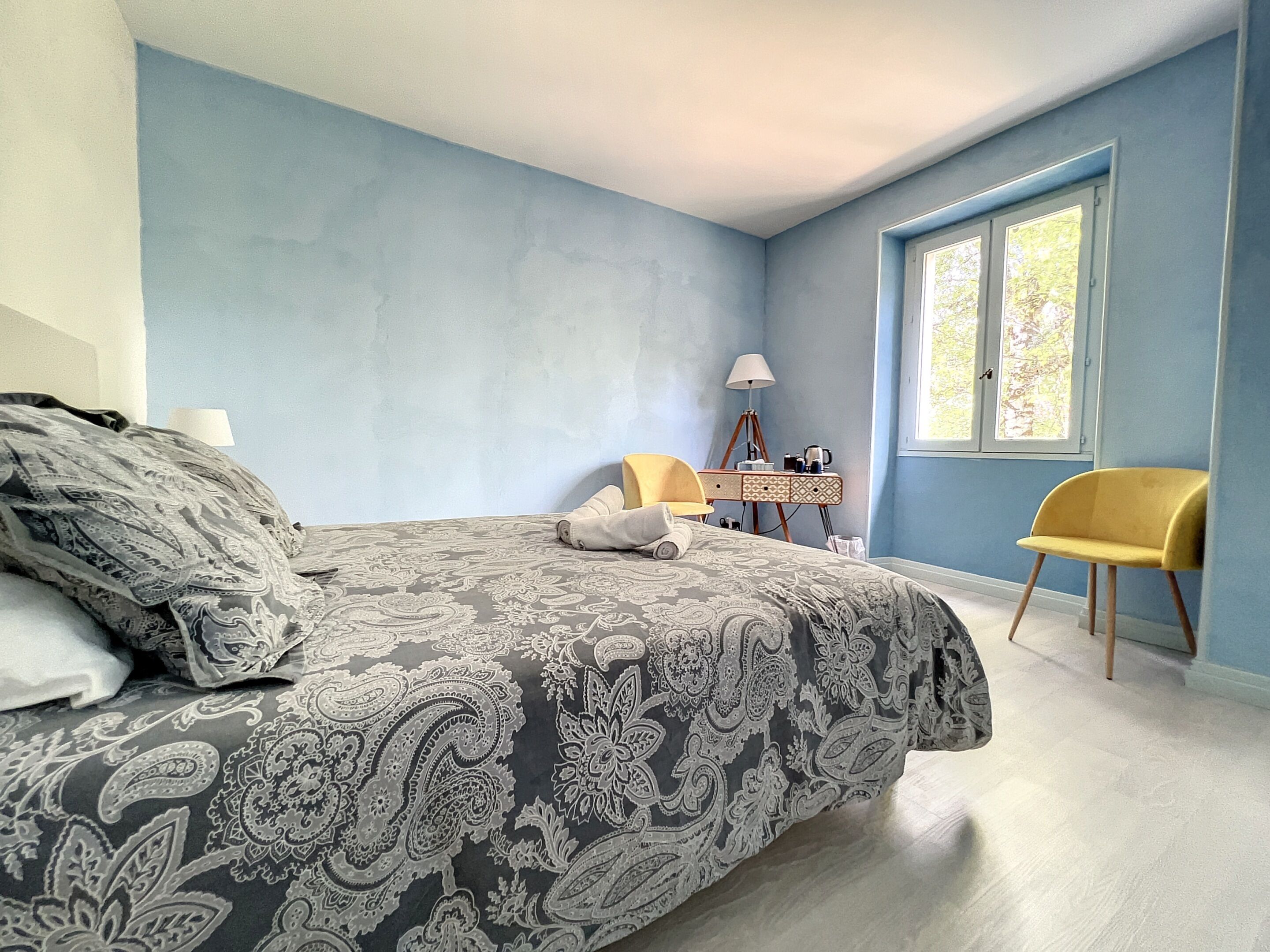 Une chambre à coucher avec un lit, un bureau, une chaise et une fenêtre.