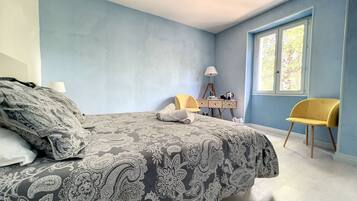 Une chambre à coucher avec un lit, un bureau, une chaise et une fenêtre.