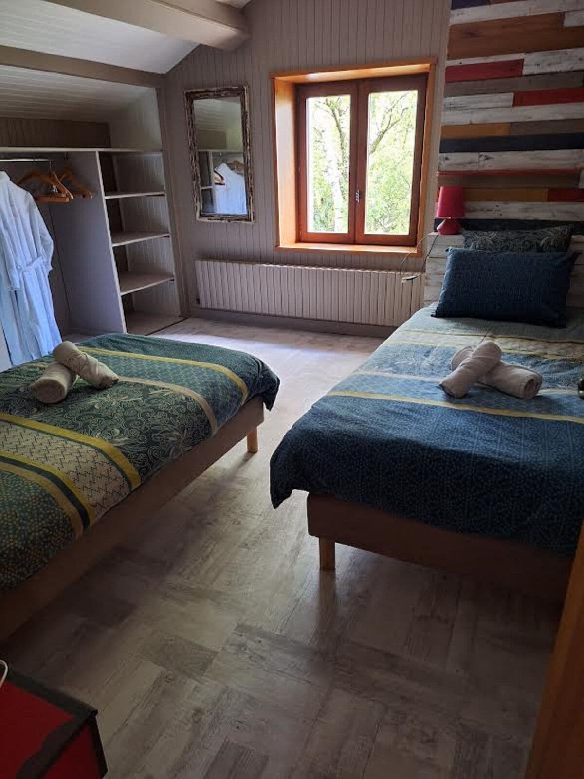 Ein Schlafzimmer mit zwei Betten, einem Fenster, einer Heizung und einem Kleiderschrank.
