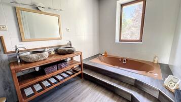 Ein modernes Badezimmer mit einem Steinsink, einem Holzwaschtisch und einer freistehenden Badewanne.