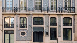 Un immeuble doté de nombreux balcons, de grandes fenêtres et d’une porte noire bien visible, portant l’inscription « ANDO Living ».