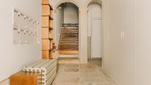 A hallway with a wooden bench, a staircase, and a wall-mounted shelf with numbered compartments. - Ando Living - Flores 25 House - 002 (Encarnação)