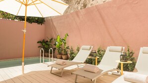 Un espace aménagé au bord de la piscine, avec des chaises longues, une piscine et des plantes en pot.
