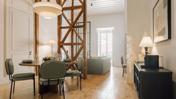 Un coin repas avec une table en bois, une table ronde entourée de chaises et un canapé en arrière-plan.