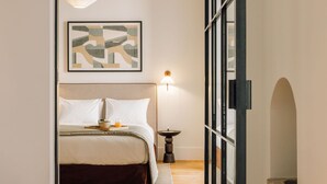 Une chambre à coucher comprenant un lit, une table de chevet, une lampe et une œuvre d’art abstraite encadrée accrochée au mur.