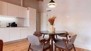 Una cocina moderna con armarios blancos, una mesa redonda de vidrio y sillas de madera.