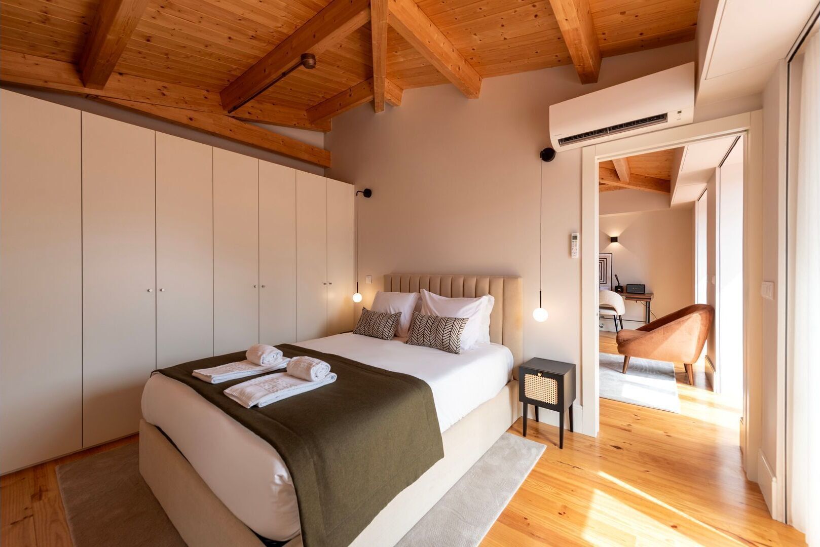 Un dormitorio con cama, mesitas de noche, un armario y vistas a otra habitación.