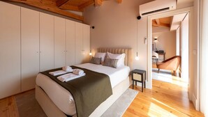 Quarto com cama, mesas de cabeceira, guarda-roupa e vista para outro espaço.