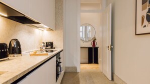 A modern kitchen with a marble countertop, a built-in oven, and a coffee machine. - Ando Living - Corpo Santo House - 203 (Lisboa)
