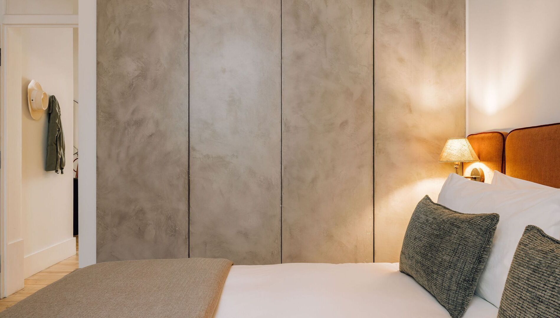 Une chambre à coucher avec un grand lit, une table de chevet avec une lampe et une armoire avec un miroir.