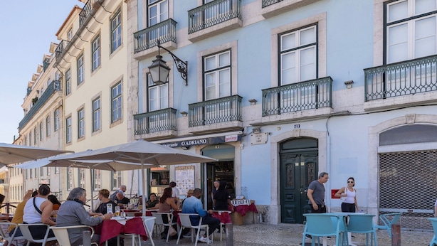 A restaurant with outdoor seating, a sign for 'OADRIANO', and a green door. - Carmo 43 | Apartment 403 (Lisboa)
