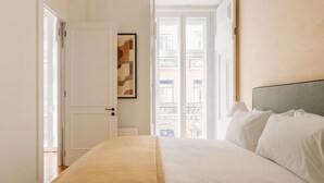 Ein Hotelzimmer mit Bett, einer Tür und Blick auf Balkone durch eine Glastür.