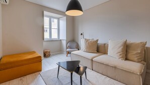 A modern living room with a sofa, a small table, a chair, and a window. - Carmo 43 | Apartment 404 (Lisboa)