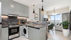 A modern kitchen with a built-in oven, washing machine, and granite countertops. - Stylish 1BR Apartment at Golf Gate (Dubai)