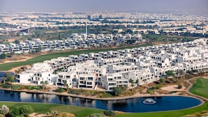 A residential area with modern apartment buildings, a golf course, and a large body of water. - Stylish 1BR Apartment at Golf Gate (Dubai)