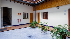 Un patio con techo de madera, suelo de baldosas y plantas en macetas.