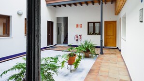 Un patio con plantas en macetas, una puerta de madera y suelo de baldosas.