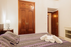 Una habitación de hotel con una cama, un armario de madera, una mesita de noche con lámpara y una chimenea.