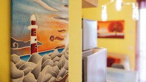Una habitación con un cuadro de un faro, televisión y refrigerador.