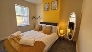 A bedroom with a bed, a window, a mirror, and two wall-mounted light fixtures. - Warm and Cosy Two bed Property /Near York City Centre (York)