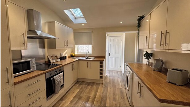 A compact kitchen with a skylight, built-in oven, microwave, and a washing machine. - Warm and Cosy Two bed Property /Near York City Centre (York)