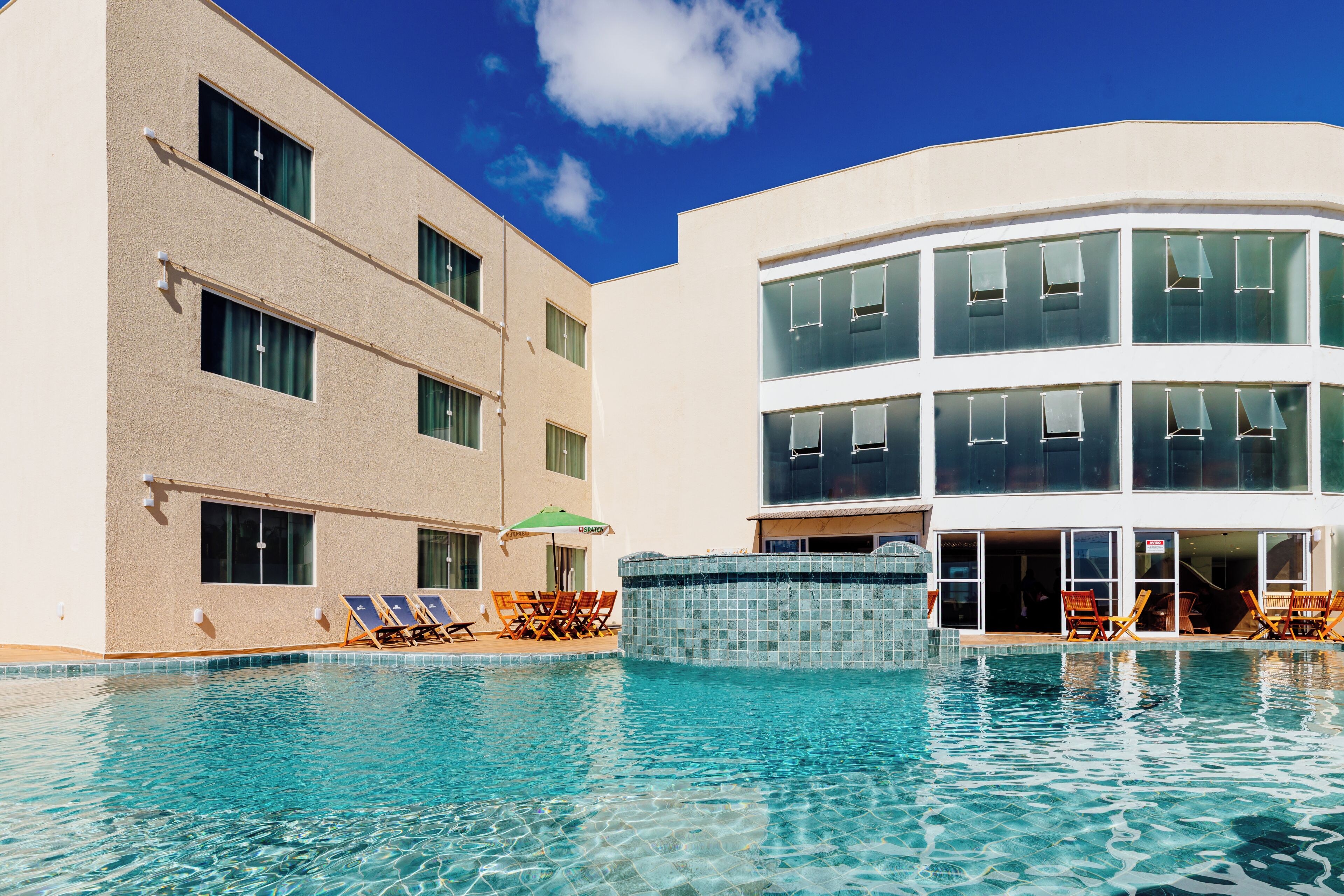 Um hotel com piscina, espreguiçadeiras e banheira de hidromassagem.