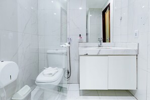 Une salle de bain moderne équipée de toilettes, d’un bidet et d’un lavabo avec un miroir.
